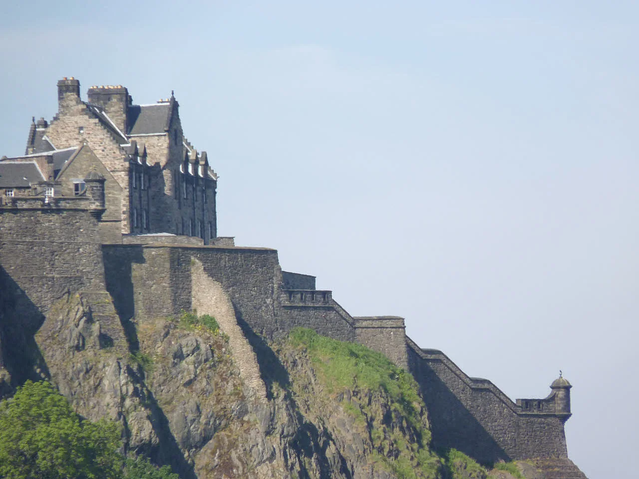 Edinburgh Castle rising above Castle Rock under a pale blue sky